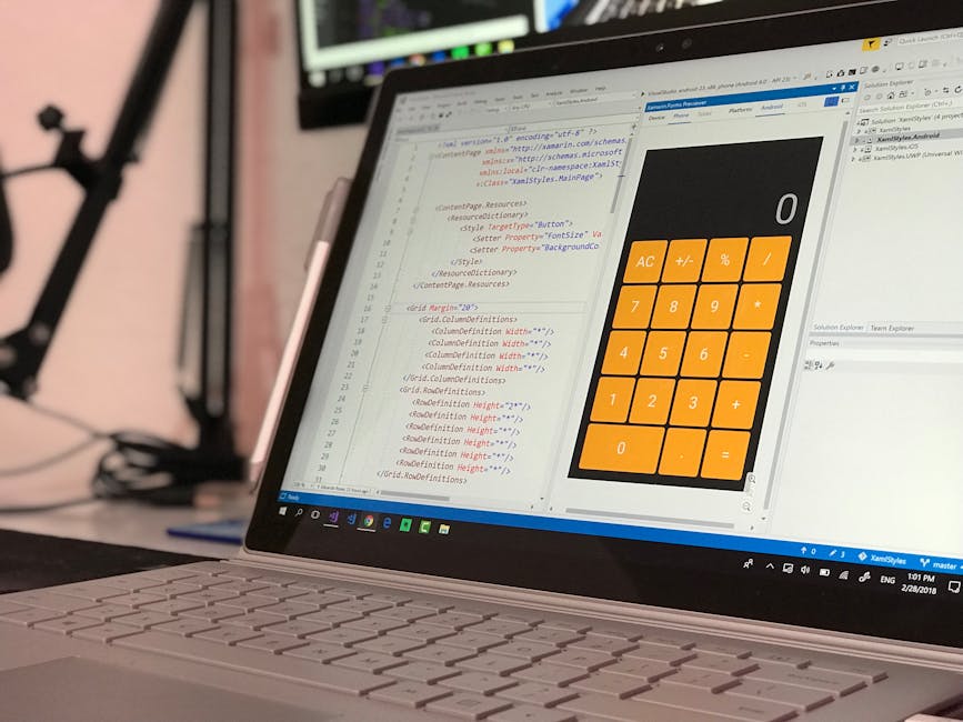 A close-up view of a laptop computer displaying a coding interface with lines of HTML and CSS code on the left side, and a simple orange calculator app with large buttons on the right side. The laptop